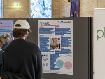 Ein junger Mann von hinten mit Basecap sieht sich die Posterausstelung bei PHKA im Rathaus an.