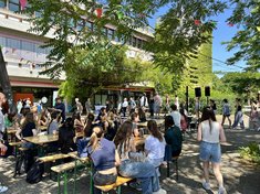 Studierende sitzen auf Bierbänken auf dem geschmückten Campus