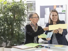 Zwei Frauen diskutieren an einem Stehtisch über die Inhalte von Karteikarten