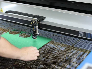 Eine Person bedient einen Lasercutter.