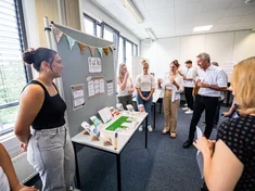 Studierendengruppen haben ihre Projekte aus dem Seminar Social Entrepreneurship in einem Seminarraum aufgebaut, die von den Jurymitgliedern begutachtet werden, u.a. vom damaligen Bürgermeister Martin Lenz.