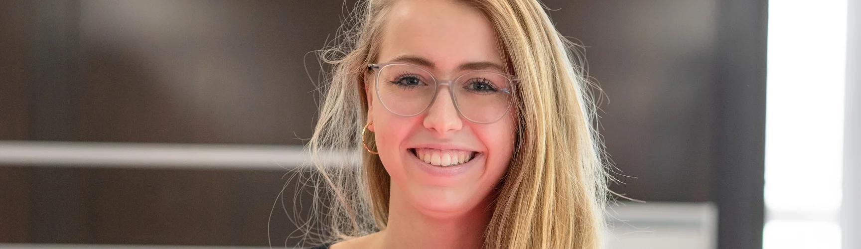 Eine fröhliche junge Frau geht mit dynamischem Schritt auf die Kamera zu