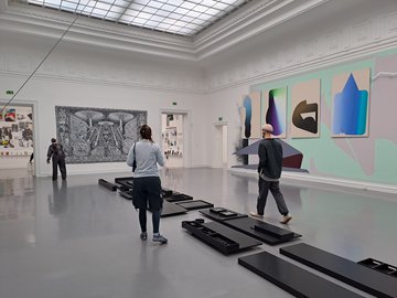 Drei Menschen betrachten Kunstwerke in einem Ausstellungsraum der Kunsthalle Baden-Baden.