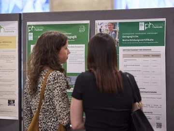 Zwei Frauen vor wissenschaftlichen Postern bei der Ausstellung im Foyer vor dem Bürgersaal im Rathaus am Marktplatz.