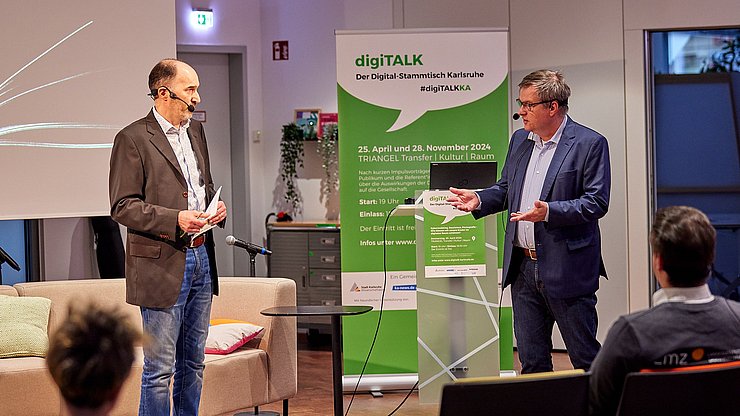 Im vom Hammer Photographie zur Verfügung gestellten Bild seiht man den Moderator Uwe Gradwohl (links) und Prof. Dr. Christian Gleser vor einem RollUp im Gespräch.