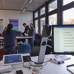 Bildschirm und Teilnehmende im Hintergrund