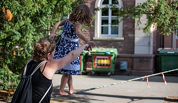 Familienfreundlicher Campus Ein Kind läuft auf auf dem PH Campus einen Seil. Es wird von einer erwachsenen Person unterstützt.